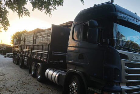 Cavalo mecânico engatado à carreta carregada, com o sol se pondo ao fundo.