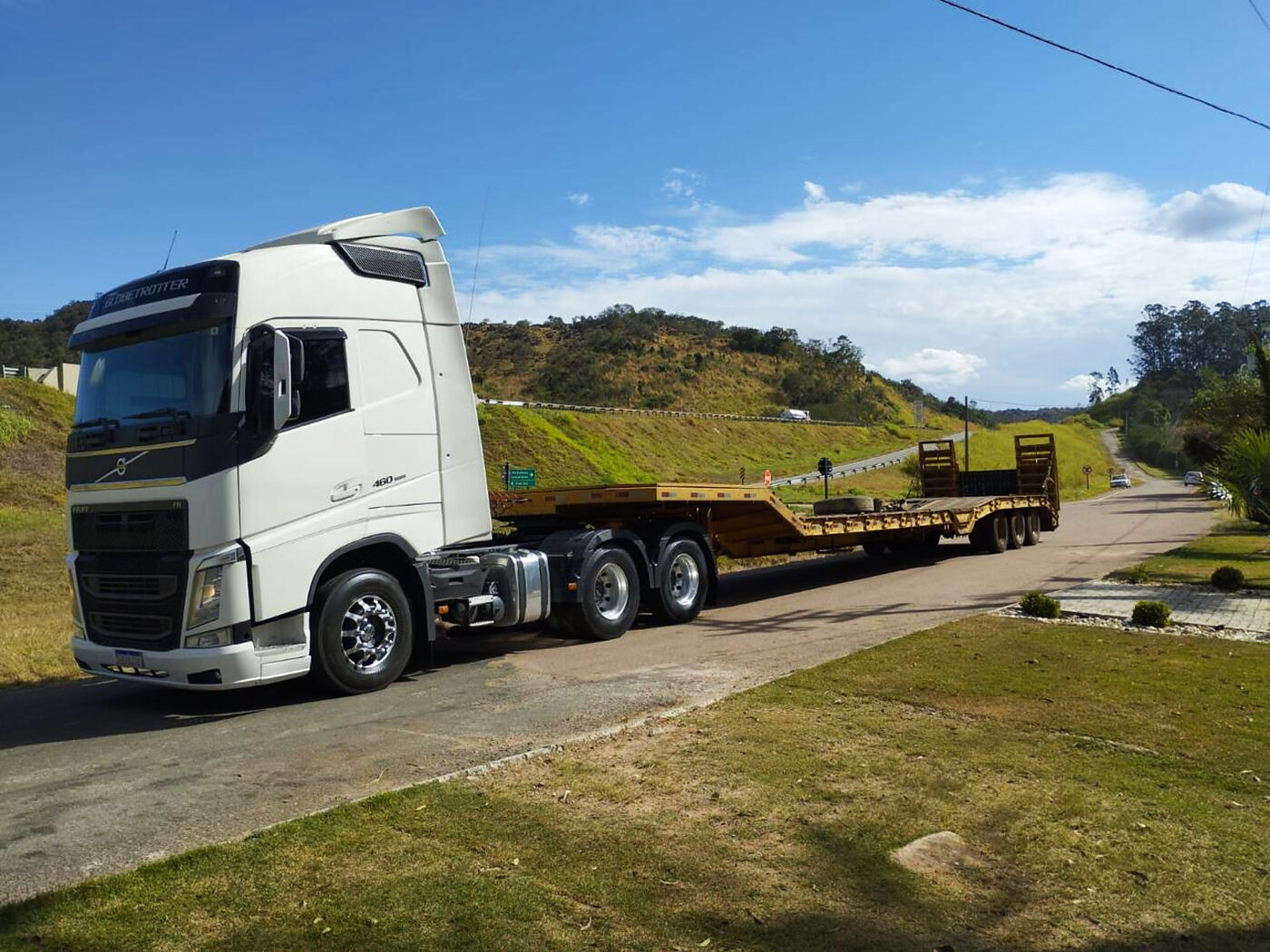Cavalo mecânico com prancha em rodovia aberta, seguindo em rota direta.